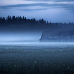A Foggy Field With A House In The Distance