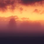 Glowing Sunset Fog Over Silhouetted Horizon During Early Evening