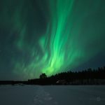 Green Aurora Borealis Dancing Over Snow Covered Field