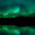 Lake Illuminated By Green Northern Lights In The Sky