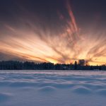 Majestic Winter Sunset Over A Snowy Landscape With Radiant Cloud Patterns