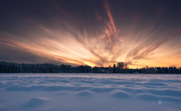 Majestic Winter Sunset Over A Snowy Landscape With Radiant Cloud Patterns