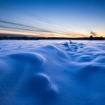 Snow-Covered Field With Wind-Swept Patterns At Twilight