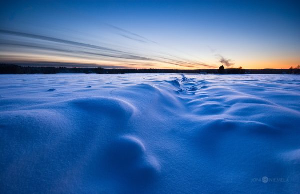 Snow-Covered Field With Wind-Swept Patterns At Twilight