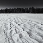 Snow-Covered Landscape Showcasing Wind-Sculpted Patterns In A Winter Setting
