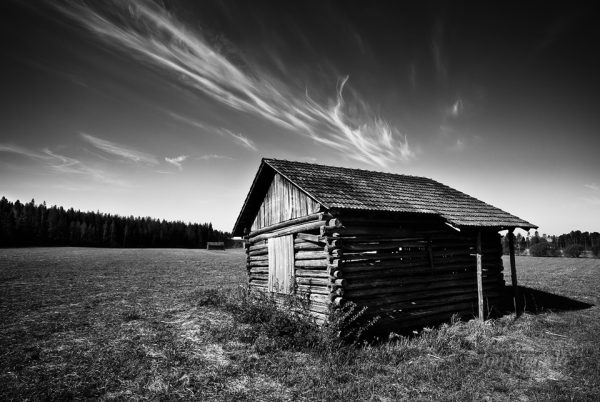 Solitary Wooden Cabin Under Dramatic Clouds In A Rural Field At Dusk