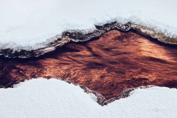 Winters Embrace: Snow-Covered Riverbanks And Ice Formations At Dusk