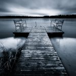 Wooden Dock Over Frozen Lake On Cloudy Day